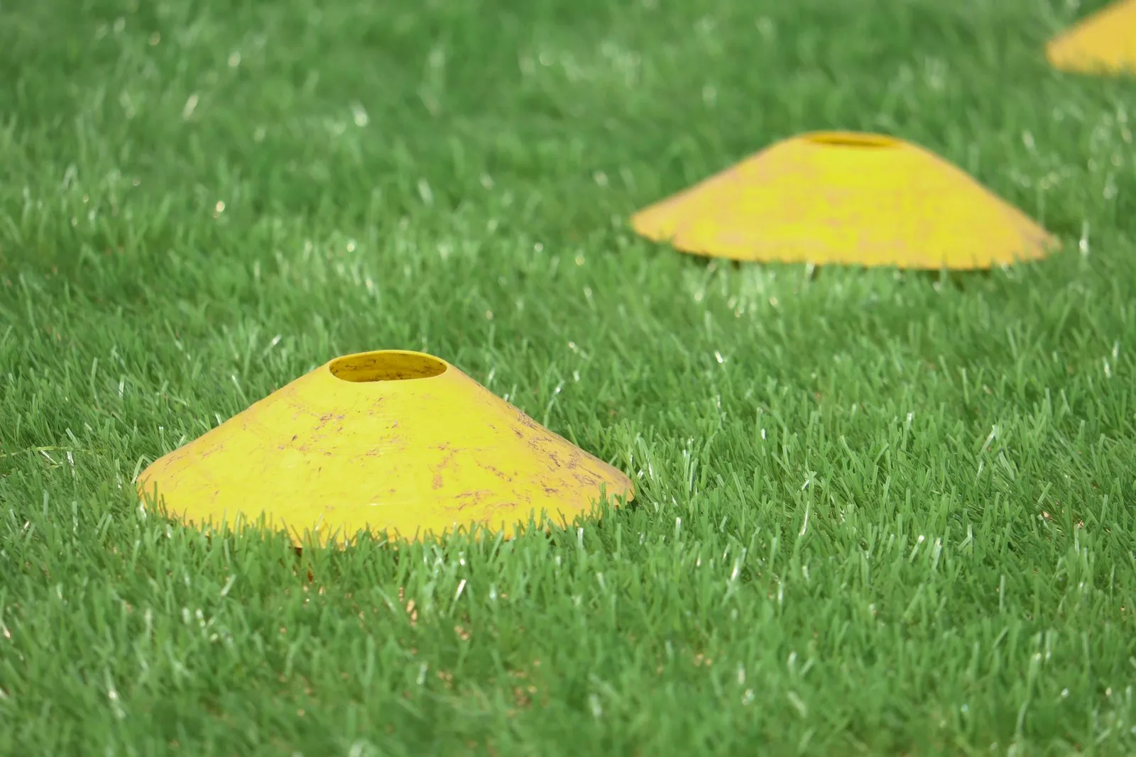 Cones de treino alinhados num relvado de futebol